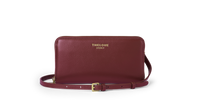 Maroon leather clutch bag with gold strap on a white background